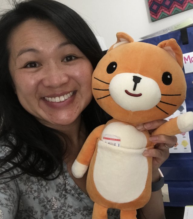 Ms. Erica smiling and holding a stuffed orange cat