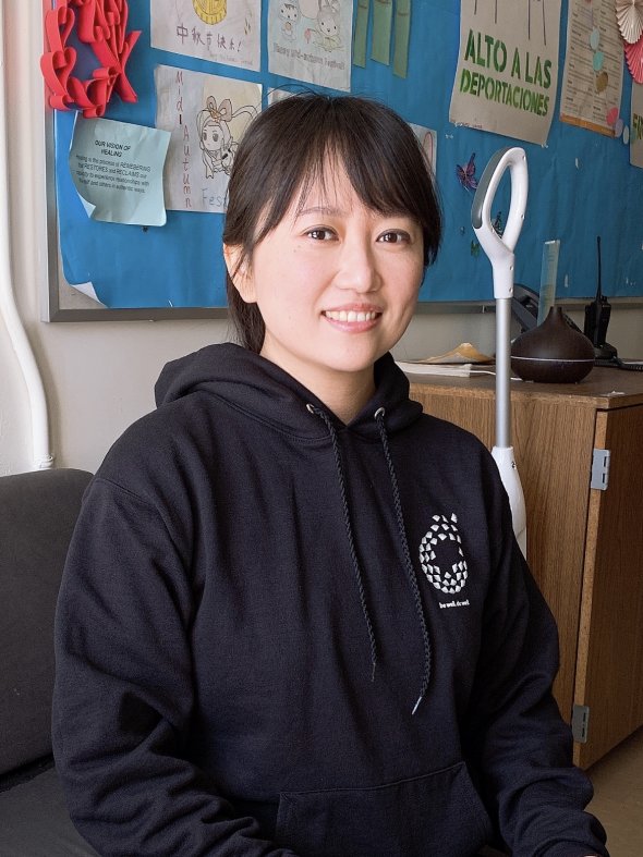 Asian woman with shoulder length hair and in a black sweatshirt with a Wellness logo.