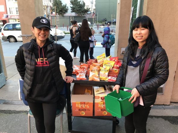 Two smiling Asian women selling snacks