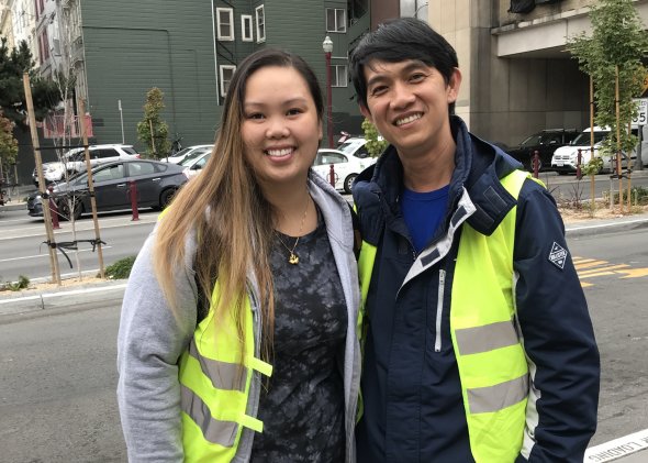 smiling asian woman and man doing drop off duty with yellow vests