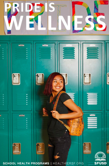 Student smiling in front of lockers with pride sign above them.