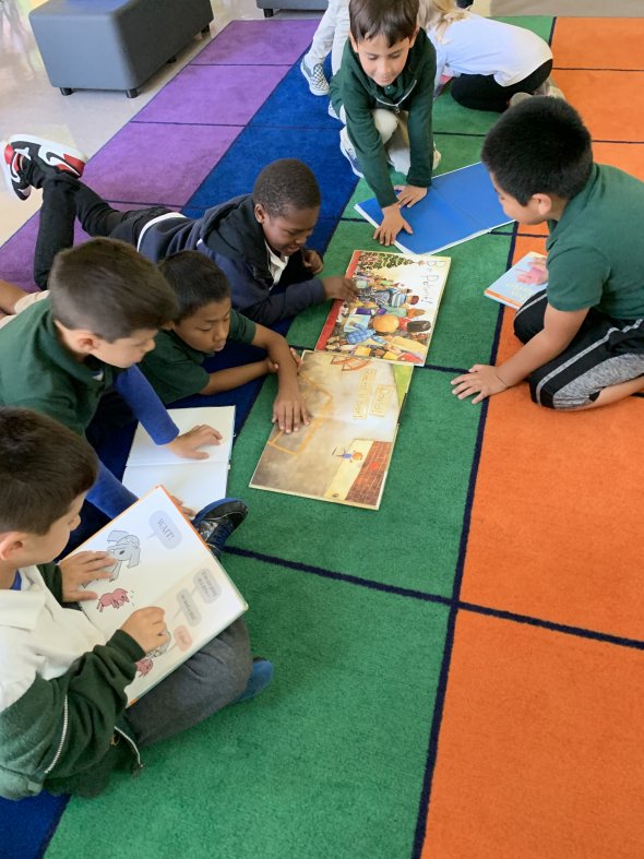 Students reading a book on the floor