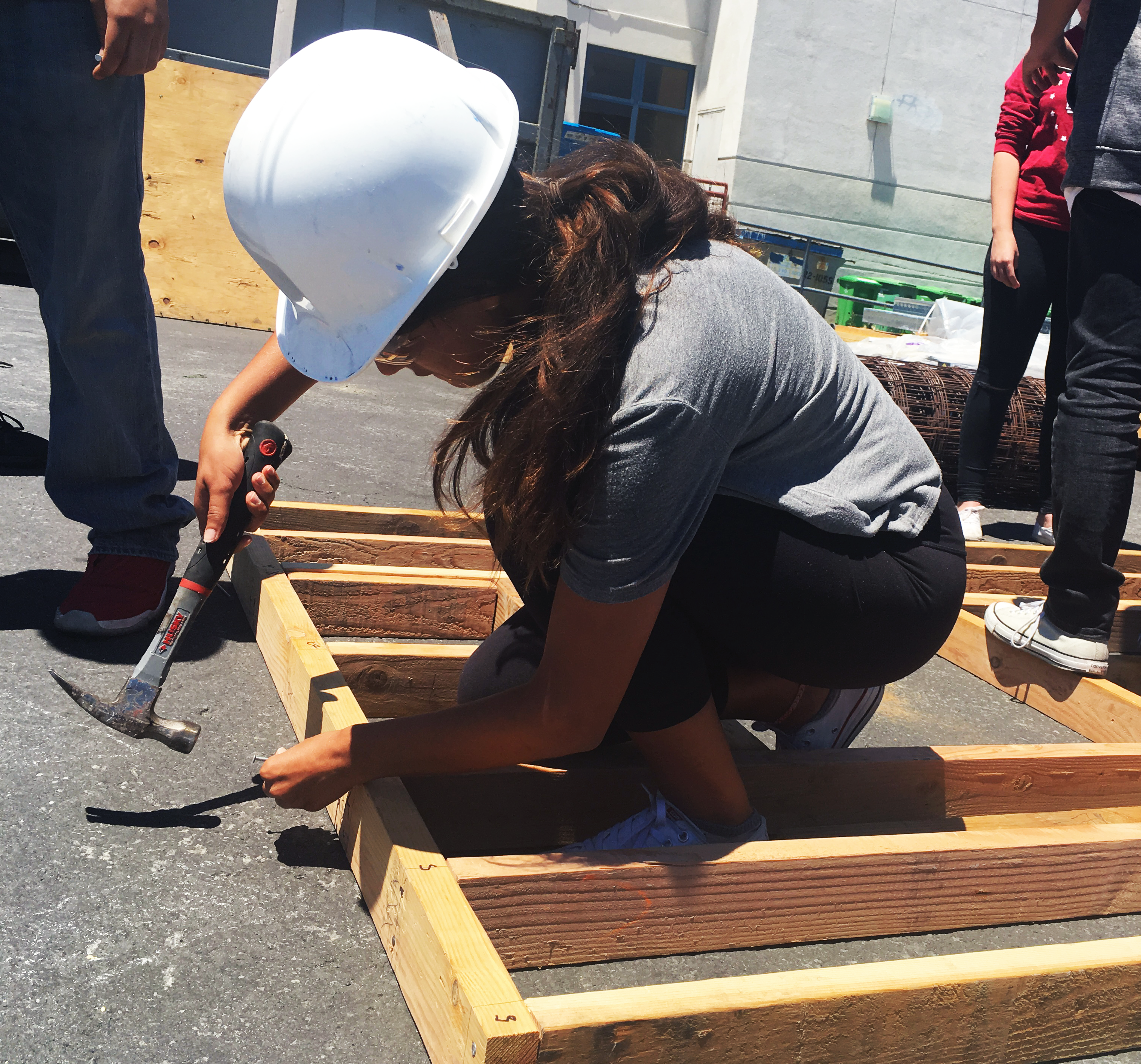 Female high school student hammering wooden frame