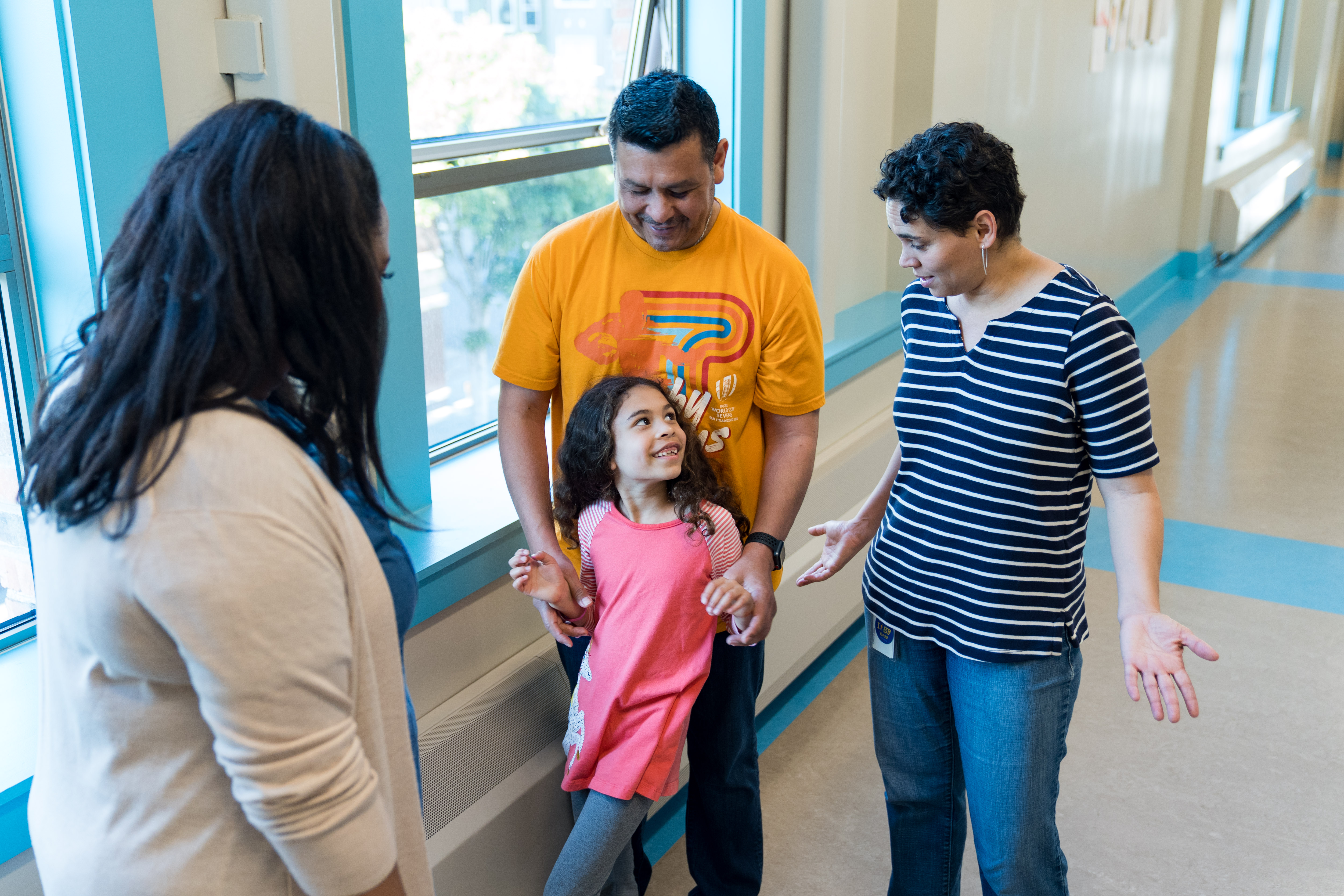 Family and teacher standing with smiling child