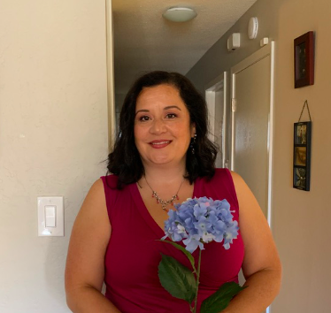 a woman presenting wearing a red dress and a light blue flower. 