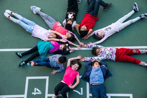 Children  in a circle lying on playground