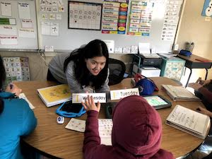 teacher showing students cards with days of the week on them