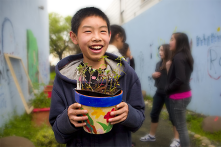 Elementary school student holding a flower pot