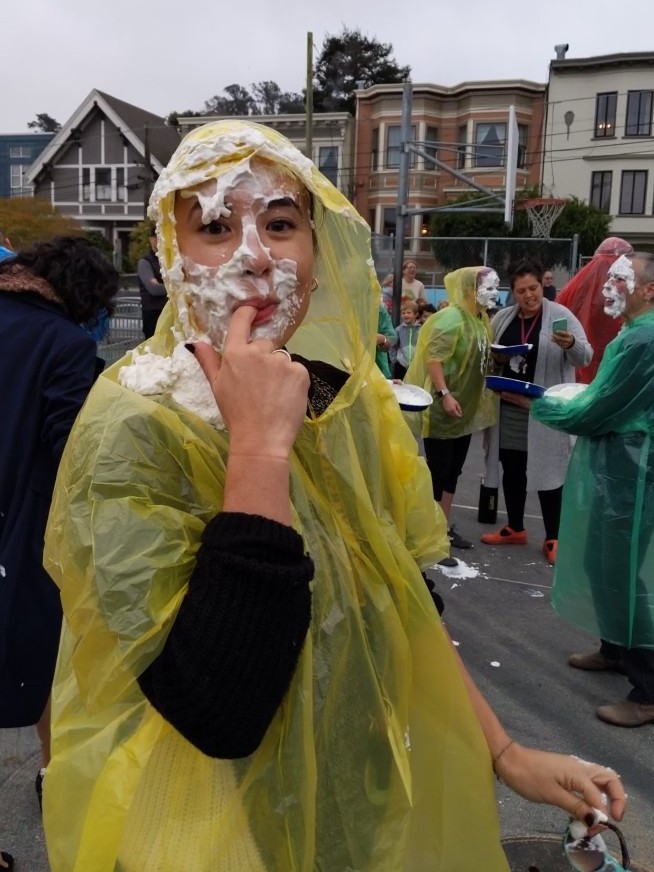 Teacher with cream pie all over her face at an outdoor school fundraising event