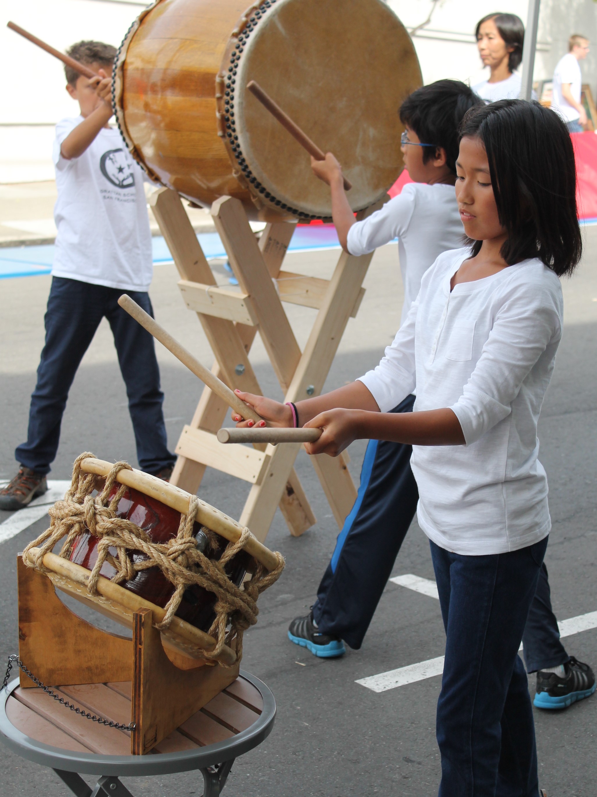 Children perform in a taiko drumming group at an outdoor neighborhood festival
