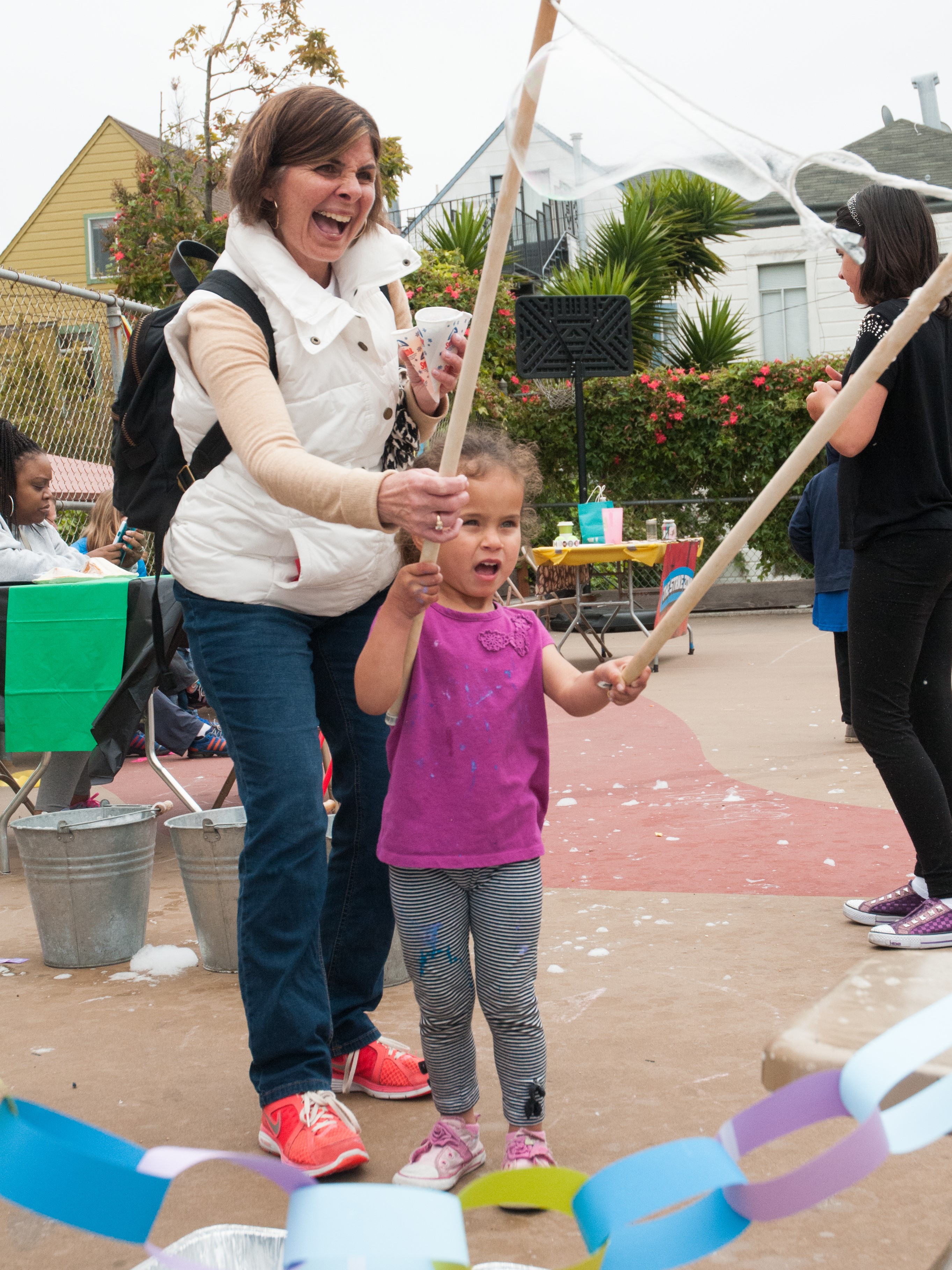 Mom and girl making giant bubbles at an outdoor school festival