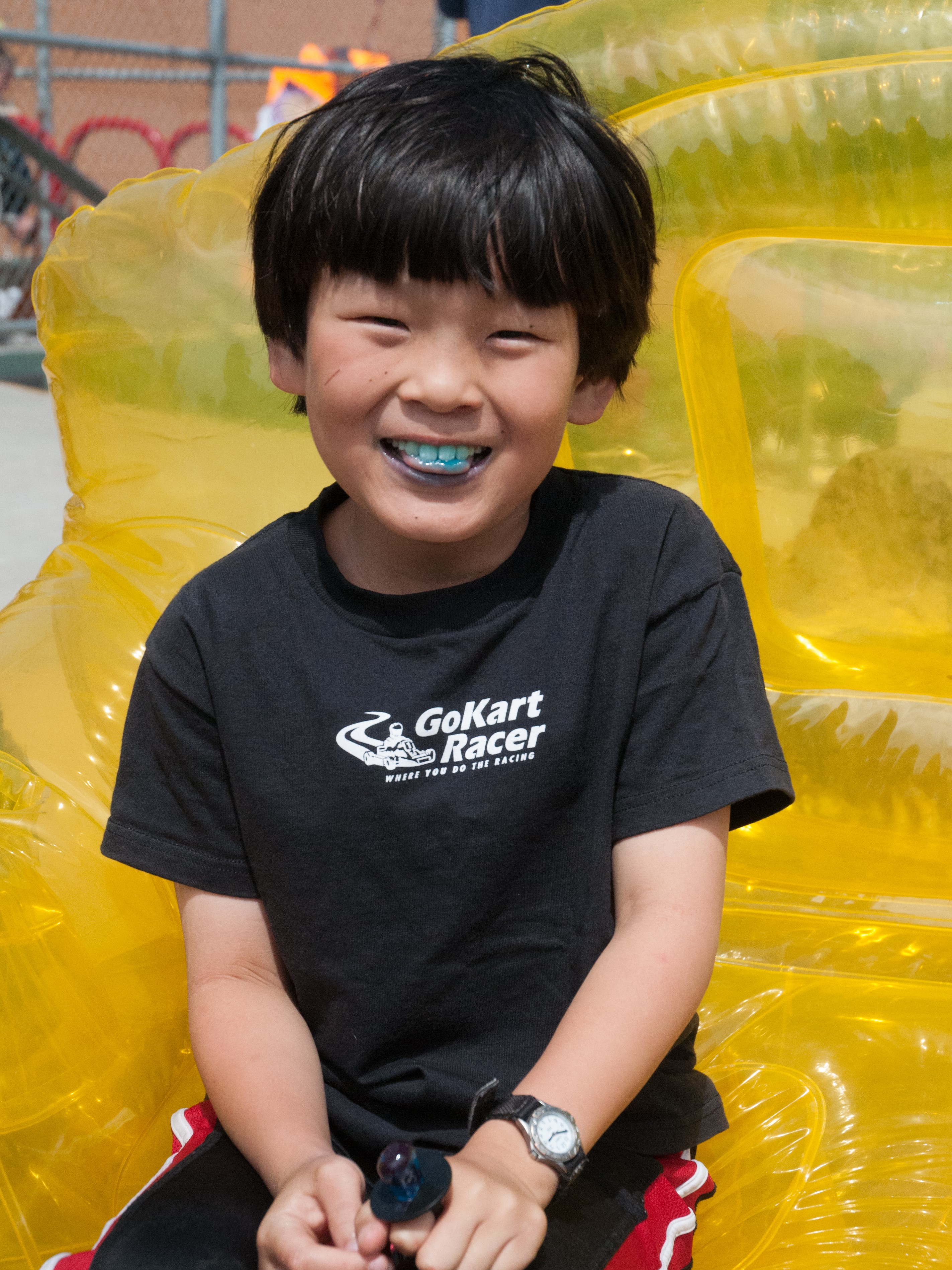 Boy with a blue tongue eating a lollipop at an outdoor school festival