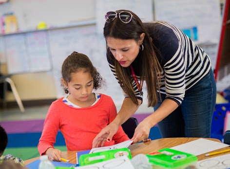 Teacher leaning over to help student