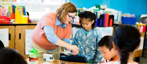 Teacher leaning over to help student