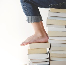 Person sitting on a large stack of books