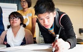 Student bent over their desk working on a paper