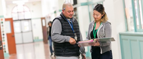 Two teachers discussing a book in the hallway