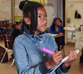 Student holding a notebook, looking up and waiting for instructions