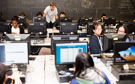 Teacher helping students in a computer lab