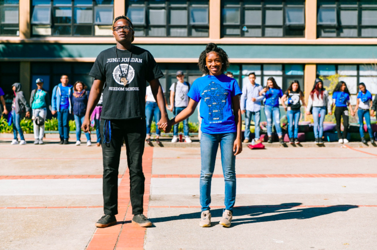 teacher and student holding hands to stand in solidarity