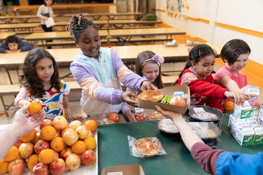 Five elementary aged students receiving school lunch. 