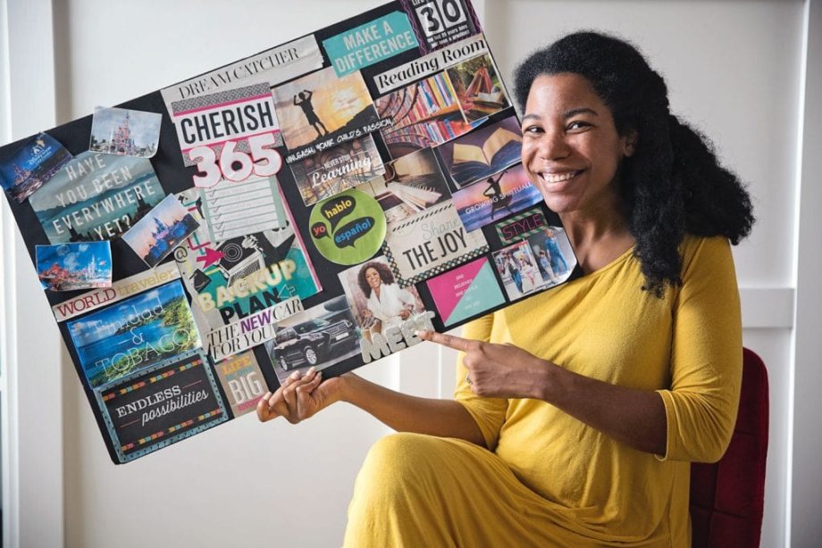 woman smiling and holding a vision board with goals
