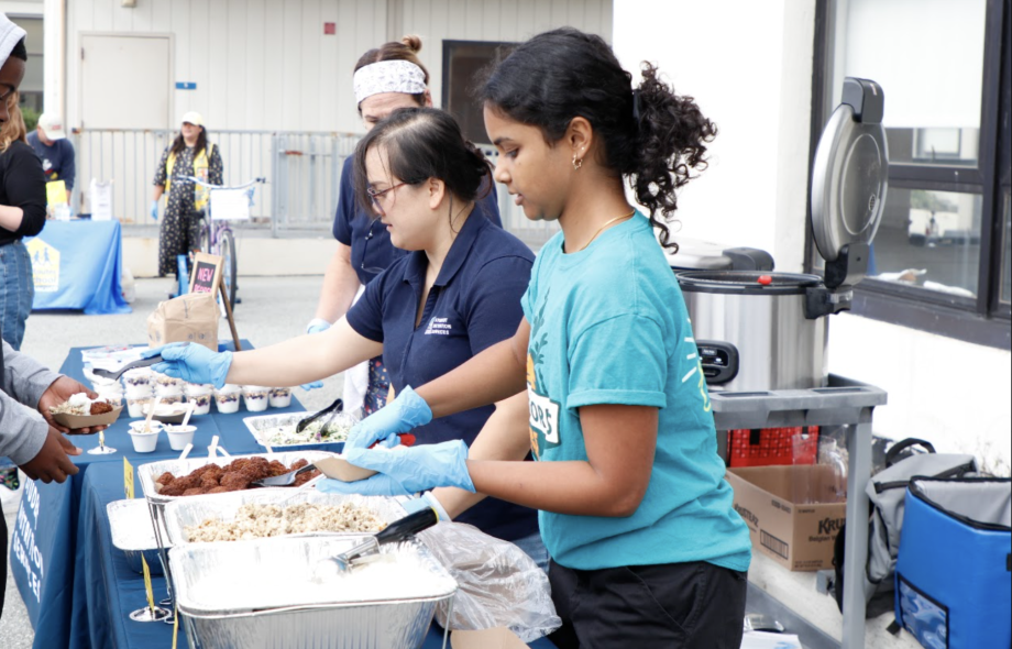 Student Nutrition Services staff serving school food samples at a community event.