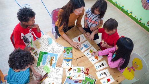 Five kindergarten students and one teacher engaged in alphabet card sorting
