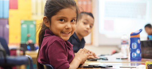 Kindergarten student seated smiling at camera