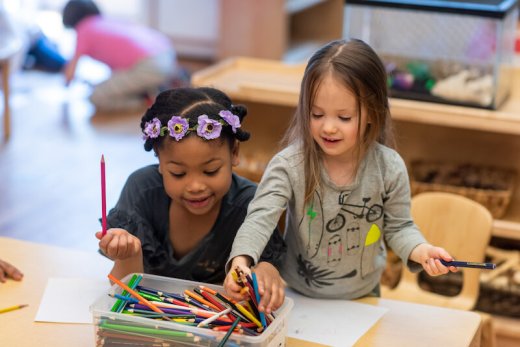 Two kindergarteners reaching for colored pencils