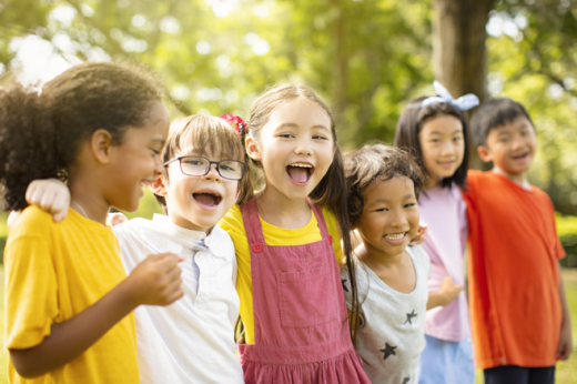 A group of kindergarteners embrace outdoors