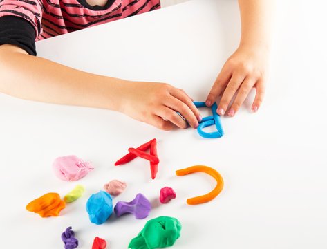 Close up of student hands forming letters out of clay