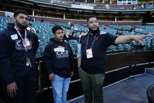 Vince Limtiaco, Human Resources Manager for the SF Giants, with Burton and Galileo seniors (John F-P and Michael R, respectively) behind home plate at Oracle Park during the CASE Study kickoff event.