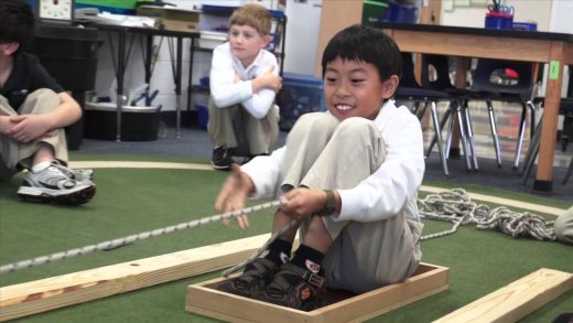 3rd grade student pulling themselves forward in a sled with a rope 