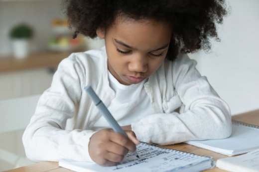 Seven-year-old sitting alone and writing in their notebook