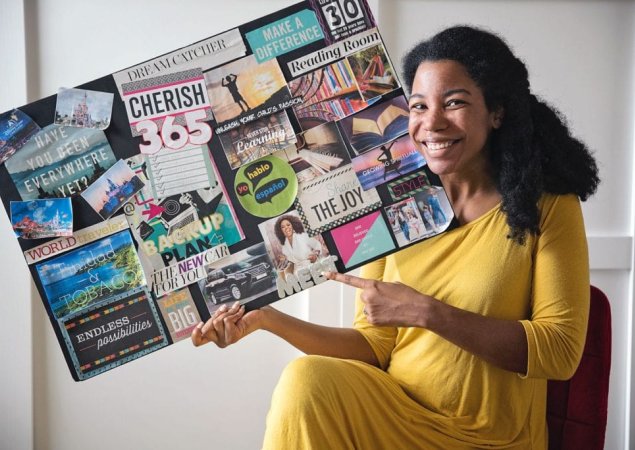 woman smiling and holding a vision board with goals