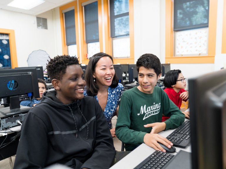 Teens and a teacher gathered around a computer