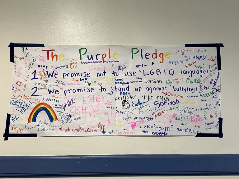 Banner titled "Purple Pledge" of student signatures pledging to stop bullying. 