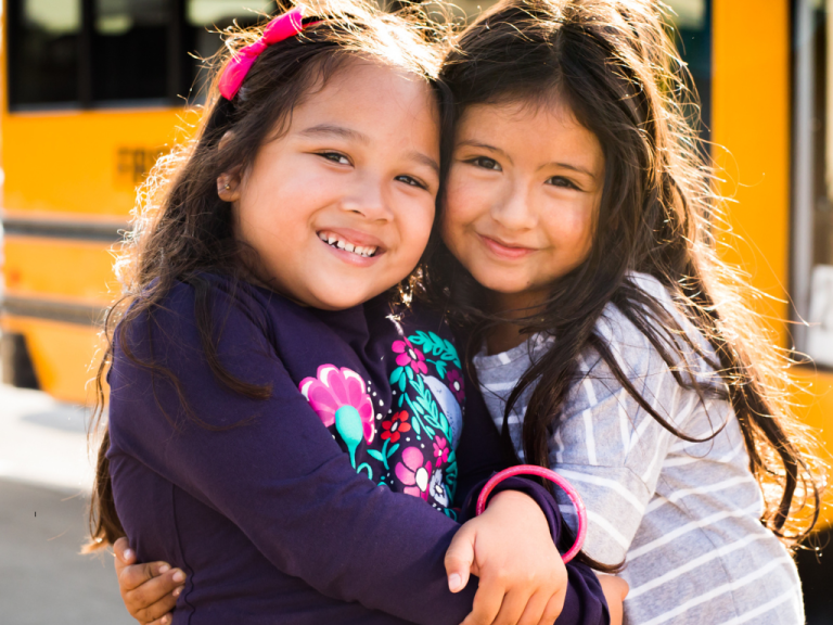 students posing in front of a school bus