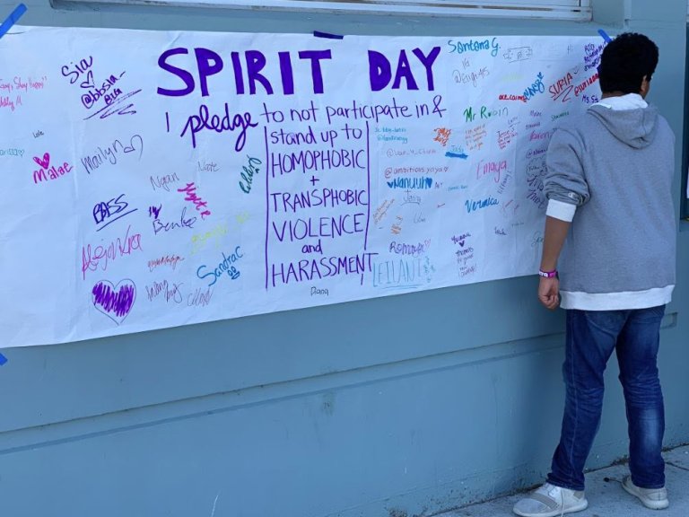Student standing in front of spirit day pledge banner.