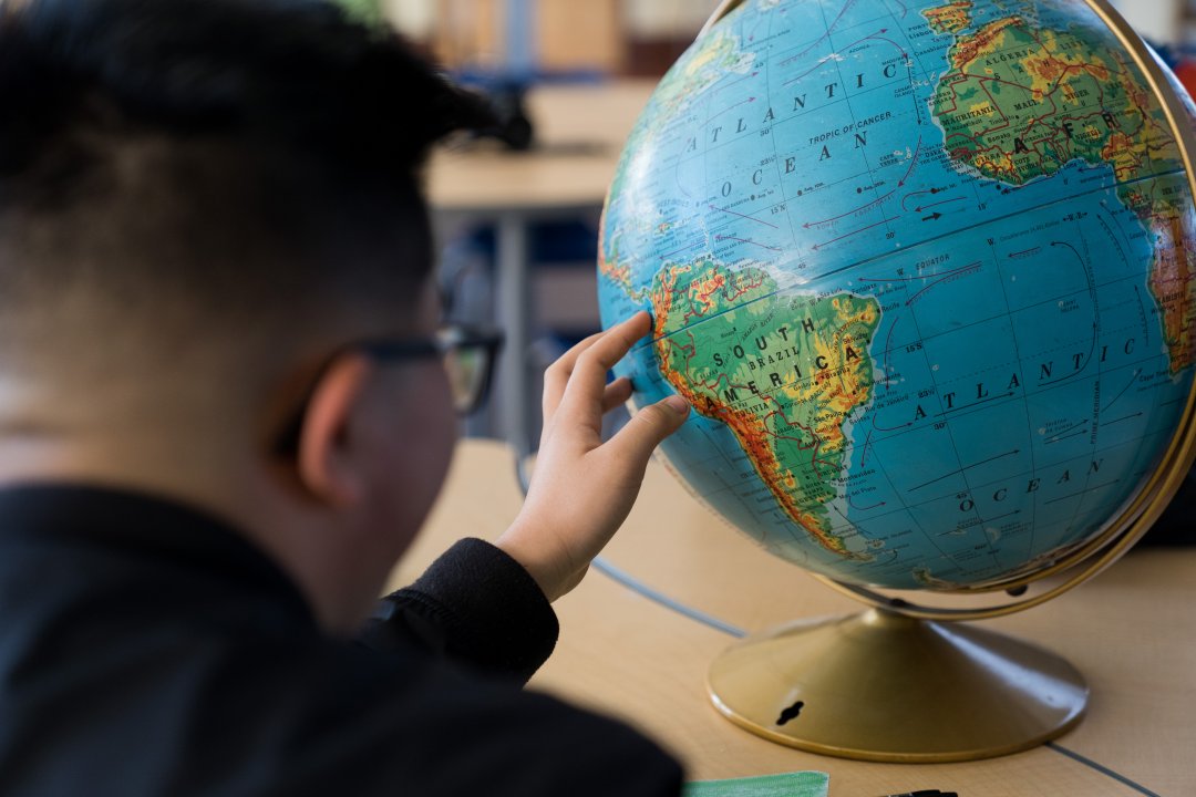 Student pointing at a globe.