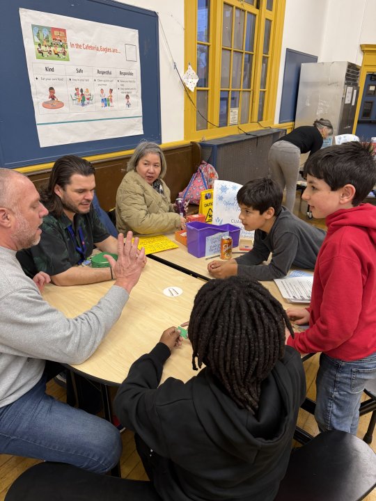 Students playing a word game with Mr. Fox around a table