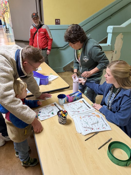 Mr. Juarez and Ms. Kinahan teaching a student how to play literacy chutes & ladders