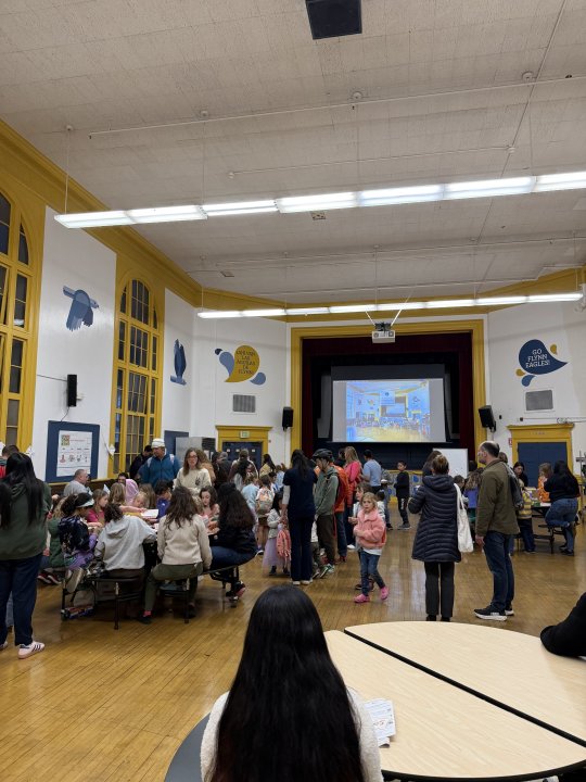 families standing in cafeteria, students sitting around table