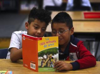 Two elementary school students reading a Spanish book