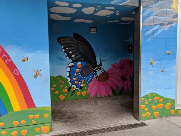 Colorful mural on exterior school wall, including painted butterfly and flowers