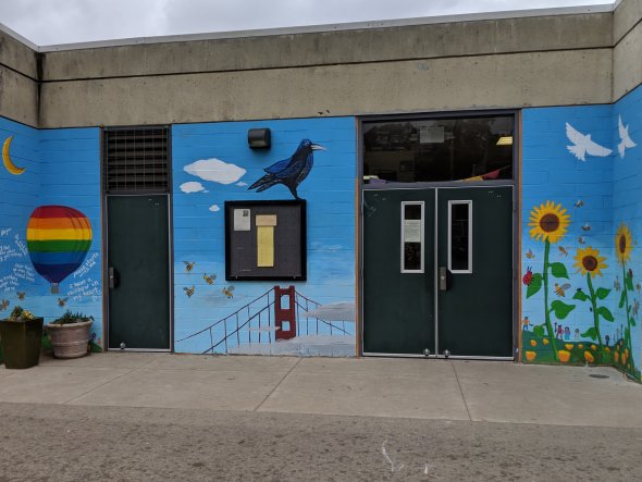 Colorful mural on exterior school wall, including painted hot air balloon and crow