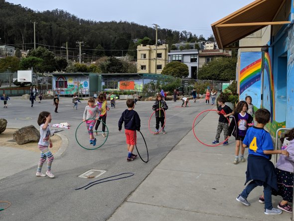 School play yard with children playing with hula hoops at recess