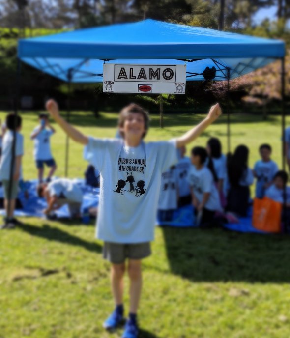 Student standing in front of Alamo tent during the 4th Grade 5K run
