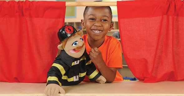 Kindergarten student playing with firefighter puppet
